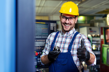 Portrait Of Male Engineer Operating CNC Machinery In Factory 
