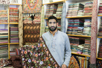 Seller from Kashmir in his colorful carpets store.Shallow doff