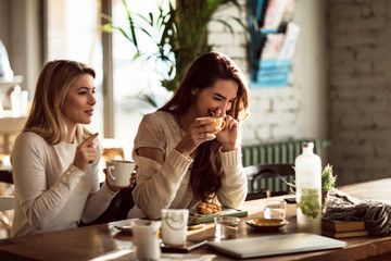 Young women laughing while talking about something funny during their coffee time.