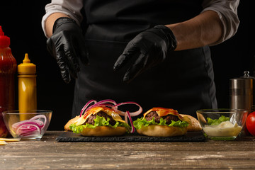The chef puts marinated onions in rings on a burger, on the background of the ingredients. Horizontal photo, Tasty and unhealthy food, fast food, homemade recipes, restaurant, catering, recipe book
