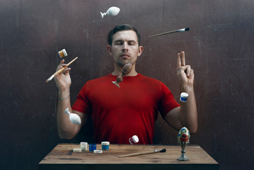 the Creator makes objects fly, the concept of preparation for Easter, a set of wooden homemade eggs, paint and brushes, a creative person in a red t-shirt,