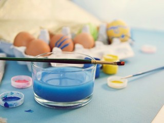 Fototapeta na wymiar Eggs, colorful paints, brushes, pencils on a blue background, coloring eggs, preparing for Easter, spring seasonal holiday