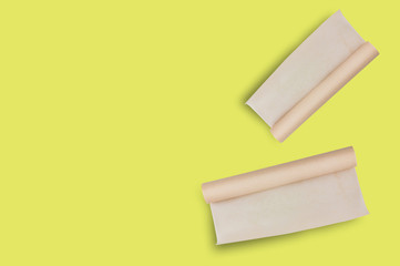 Two rolls of brown baker paper on yellow table on cuisine with copy space for your text. Top view....