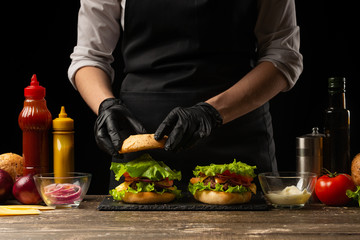 the chef prepares a burger, a hamburger. on a background with ingredients. Delicious and fast food,...