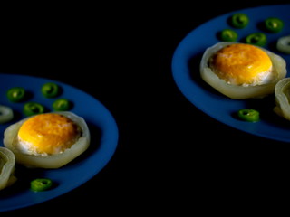 Little scrambled eggs on a blue plate. Fried eggs with bitter pepper.