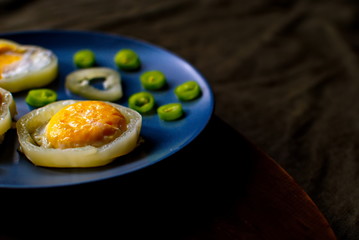 Little scrambled eggs on a blue plate. Fried eggs with bitter pepper.