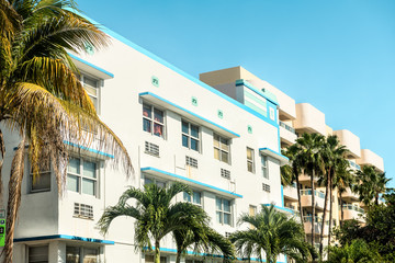 White, blue, teal, turquoise, yellow buildings in Art Deco district in South Beach of Miami, Florida during sunny day with palm trees, balconies, windows