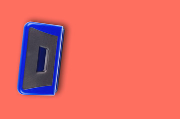 One blue metallic hole puncher on office table or school desk living coral color. Copy space for...