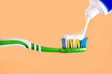 Toothbrush squeezed on toothbrush toothpaste Orange background