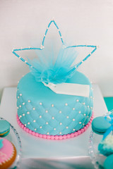 Blue and pink birthday cake with pearls big crown for little baby girl and decorations for party