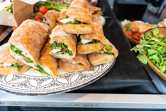 Closeup of fresh display of stacked pile of panini bread mozzarella melted cheese sandwiches and vegetarian italian arugula in store shop cafe buffet catering