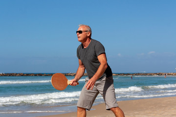 portrait of a man playing beach tennis