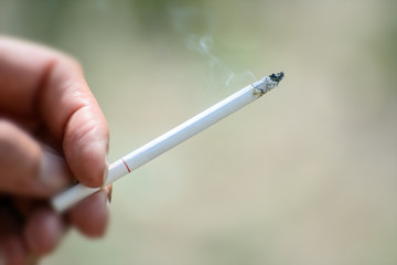 Female fingers smoking cigarette on a green background