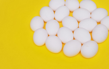 White chicken eggs on yellow background. 