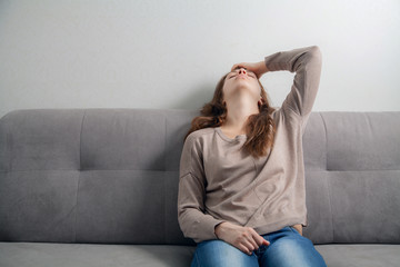  Young woman sitting on the couch depressed.