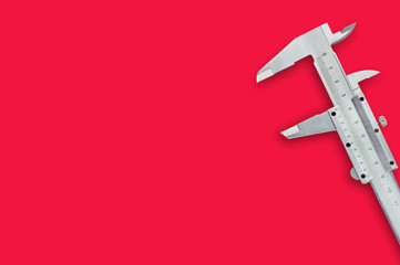 One metal vernier caliper on red table with copy space for your text. Top view. Industrial concept