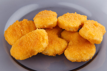 Chicken nuggets with cheese on a glass plate.