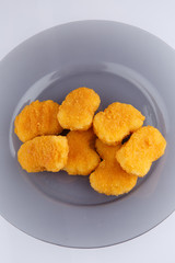Chicken nuggets with cheese on a glass plate.