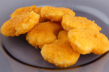 Chicken nuggets with cheese on a glass plate.