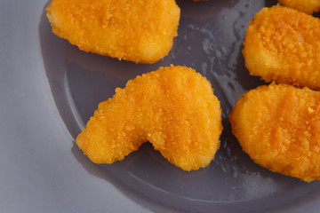 Chicken nuggets with cheese on a glass plate.