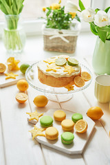 Fototapeta na wymiar Naked cake with lemons and limes. Lemonade and flowers tulips on table. Mason jar glass of lemonade with lemons and straw. Copy space. Concept of spring and summer season. Healthy Food and Drink