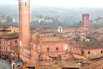 Misty city with 14th century tower Torre del Mangia, Siena of Italy. Tuscany city roofs and old...