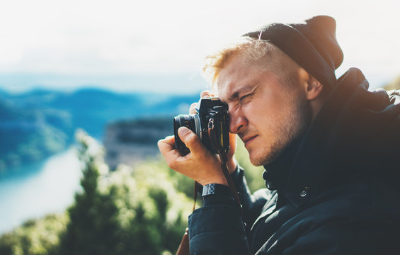 hipster tourist hold in hands taking photography click on retro vintage photo camera in auto, photographer looking on camera technology, panoramic landscape vacation concept, sun flare mountain