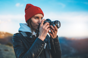 hipster tourist girl hold in hands take photography click on modern photo camera, photographer look on camera technology, journey landscape vacation concept, sun flare mountain - obrazy, fototapety, plakaty