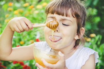 The child eats honey. Selective focus. nature.