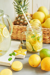 Lemonade and flowers tulips on table. Mason jar glass of lemonade with lemons and straw. Copy space. Fruits and macaroons on the table. The concept of spring and summer season.Healthy Food and Drink