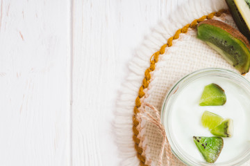 Obraz na płótnie Canvas Yogurt with kiwi slices on a wooden white background.