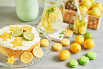 Naked cake with lemons and limes. Lemonade and flowers tulips on table. Mason jar glass of lemonade with lemons and straw. Copy space. Concept of spring and summer season. Healthy Food and Drink