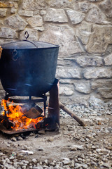 Traditional cooking chef in a cast iron cauldron. Food on an open flame. Cooking pan for many...
