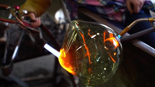 A glass blower working on a piece of glass art