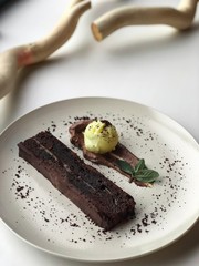  Chocolate dessert cake on a white plate next to wooden twigs