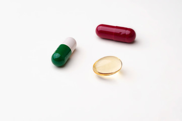 Colored tablets and capsules on white background