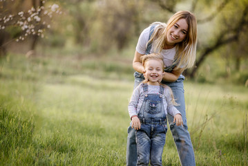 young mother with adorable daughter in park with blossom tree