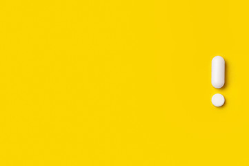 White tablets on yellow background. exclamation mark