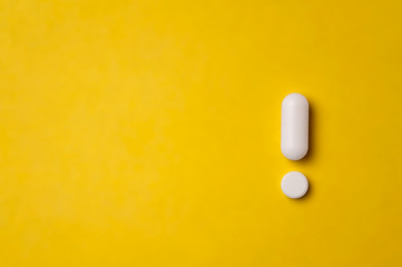 White tablets on yellow background. exclamation mark