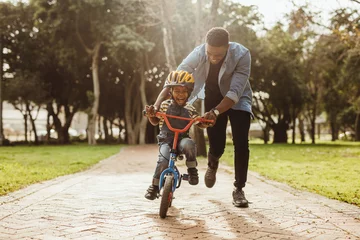 Foto op Plexiglas Father teaching his son cycling at park © Jacob Lund