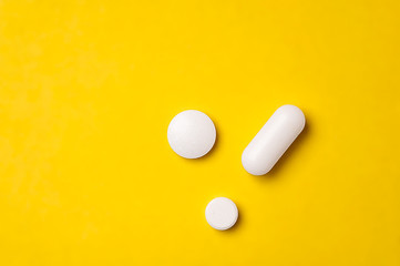 White tablets on yellow background. Different size and shape