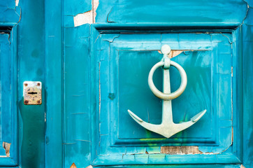 old anchor-shaped door handle on a weathered door © Francesca