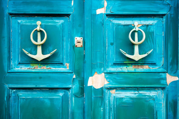 old anchor-shaped door handles on a weathered door