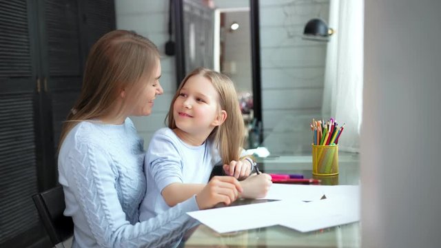 Happy mother and baby daughter enjoying drawing picture on paper using colorful pencil