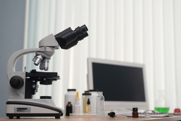 Pharmacology background. Medicine. Laboratory table with a blank screen computer, microscope and various flasks above.
