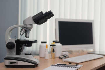 Pharmacology background. Medicine. Laboratory table with a blank screen computer, microscope and various flasks above.