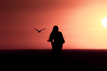 Sunset silhouette: same sex couple of girls at sunset in Camps Bay Tidal Pool, Cape Town, South...