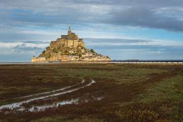 Mont Saint Michel, famous and beautiful Island with historical Abbey, panoramatic view from land over the field, cloudy weather, Normandy, northern France