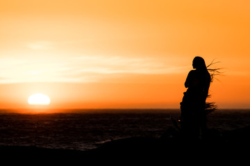 Fototapeta na wymiar Sunset silhouette: same sex couple of girls at sunset in Camps Bay Tidal Pool, Cape Town, South Africa