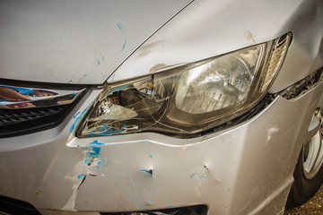 Close-up front of new silver car distorted by accident. Crashed new silver car severely damaged and...